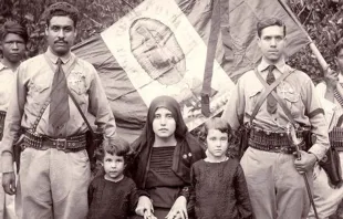 Cristeros junto a familiares, con la bandera de México detrás con la imagen de la Virgen de Guadalupe como escudo. Foto: Dominio público. 