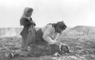 Una mujer armenia arrodillada ante un niño fallecido por el Genocidio Armenio. Foto: dominio público 