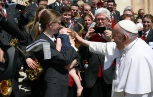 El Papa saluda a la hija de un miembro de la orquesta tras la Audiencia General. Crédito: Vatican Media. 