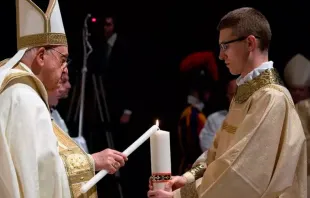 Zane sostiene el cirio pascual mientras el Papa Francisco lo enciende, en la Vigilia Pascual del Sábado Santo 2023 en el Vaticano. Crédito: Zane Langenbrunner via CNA 