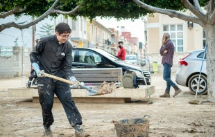 Un sacerdote recoge el lodo en una de las zonas devastadas en España por las tormentas. Crédito: V. Gutiérrez / Arzobispado de Valencia.