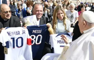 El P. Omar Raposo y la pareja de esposos Carla y Rodrigo Ferro entregan camisetas de jugadores del PSG al Papa Francisc.o Crédito: Vatican News
