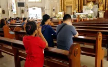 Hombres y mujeres católicos se arrodillan y rezan dentro de la Catedral de Antipolo en Filipinas.
