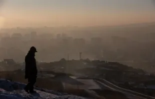 Fotografía tomada el 16 de enero de 2022 muestra a un hombre observando el humo que se cierne sobre las casas en Ulán Bator, la capital de Mongolia. Crédito: Byambasuren Byamba-Ochir/AFP vía Getty Images