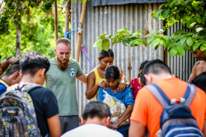 Equipo misionero rezando en pueblo guatemalteco.