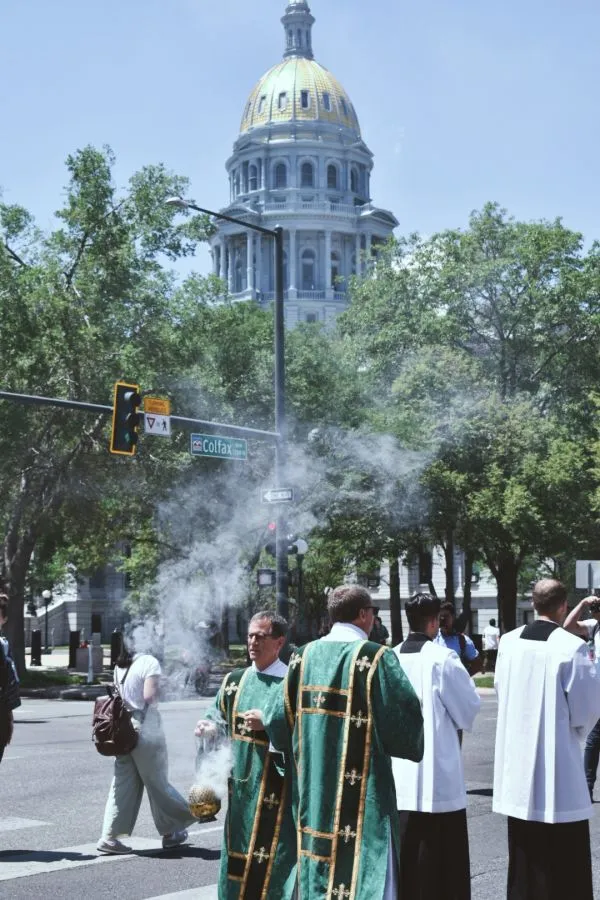 Un diácono esparce incienso durante la procesión eucarística, frente a la custodia, mientras otro sacerdote le guía frente al capitolio del estado de Colorado el 9 de junio de 2024. Crédito: Kate Quiñones/CNA.
