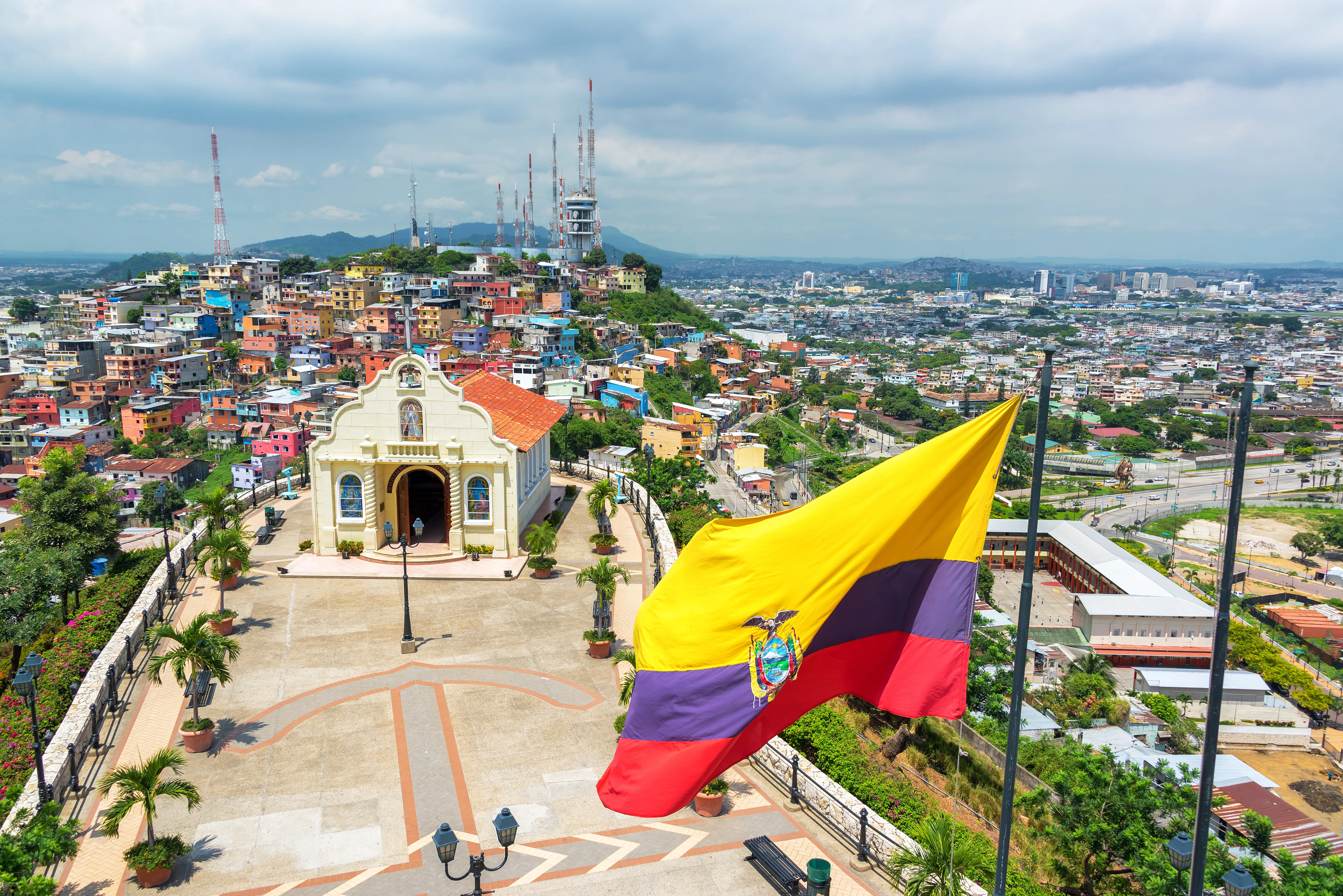 Bandera ecuatoriana en la cima de la colina de Santa Ana con una iglesia y la ciudad de Guayaquil visible en el fondo.?w=200&h=150