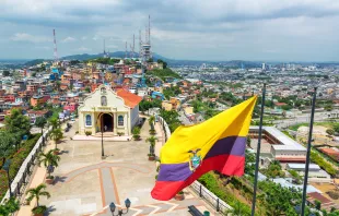 Bandera ecuatoriana en la cima de la colina de Santa Ana con una iglesia y la ciudad de Guayaquil visible en el fondo. Crédito: Shutterstock