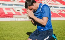 Imagen referencial de un futbolista rezando