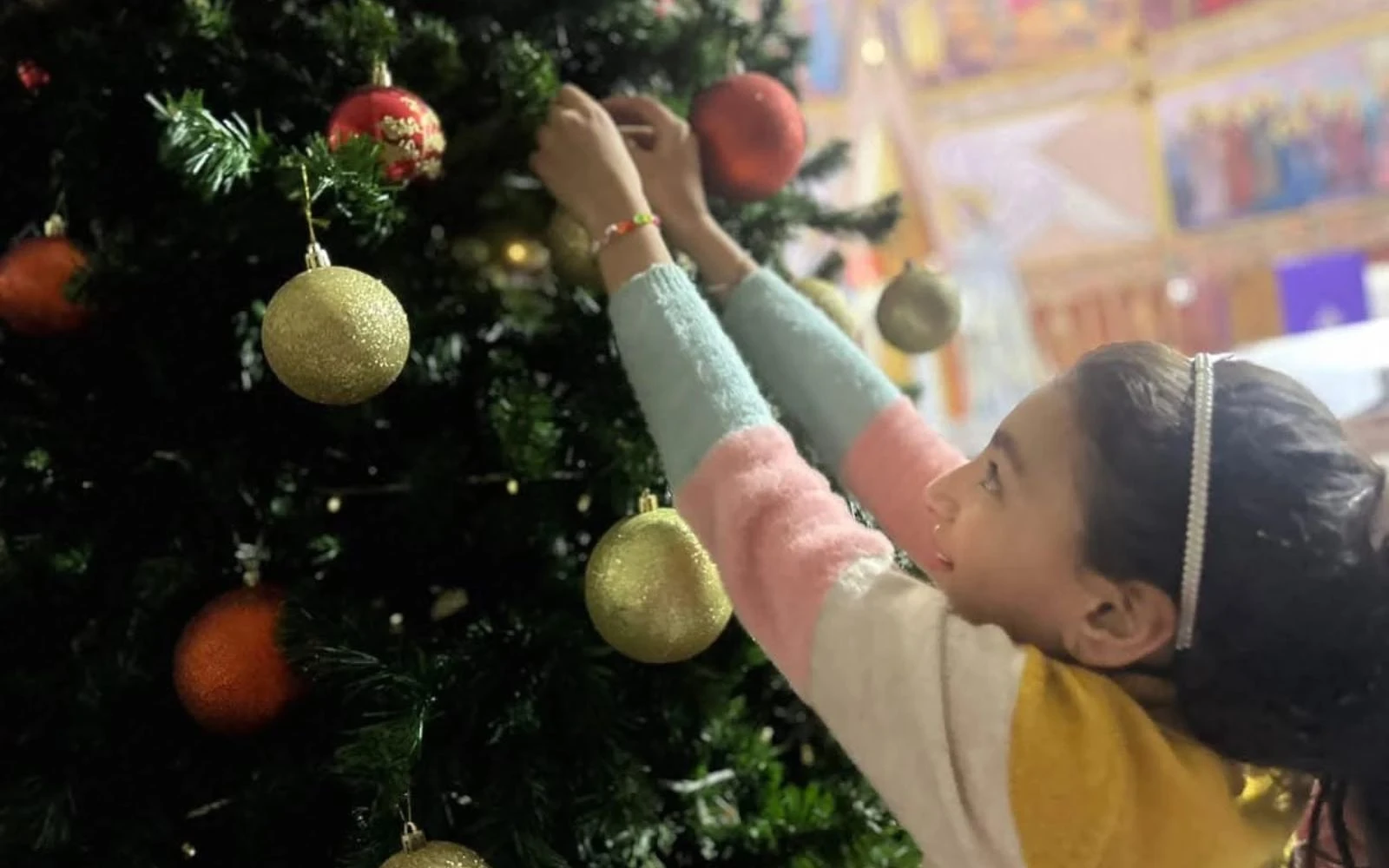 Una niña cuelga un adorno en el árbol de Navidad de la iglesia de la Sagrada Familia en Gaza.?w=200&h=150