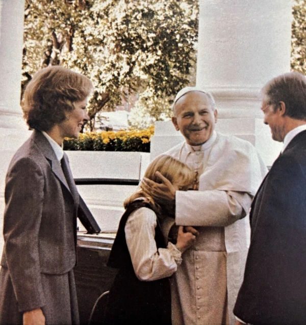 Under the radiant gaze of US President Jimmy Carter and First Lady Rosalynn Carter, Pope Saint John Paul II greets their then 11-year-old daughter Amy Carter upon her arrival at the White House on October 6, 1979. Credit: US Government Printing Office.