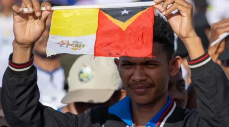 Joven de Timor Oriental levanta la bandera del Vaticano junto a la de su país en la Misa del Papa Francisco en Taci Tolu