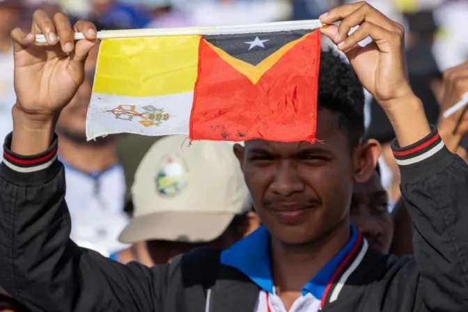 Joven de Timor Oriental levanta la bandera del Vaticano junto a la de su país en la Misa del Papa Francisco en Taci Tolu