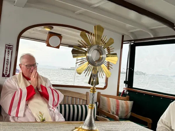 El Cardenal Timothy Dolan, Arzobispo de Nueva York reza ante la Eucaristía mientras es transportada en barco junto a la Estatua de la Libertad. Crédito: Jeffrey Bruno/CNA
