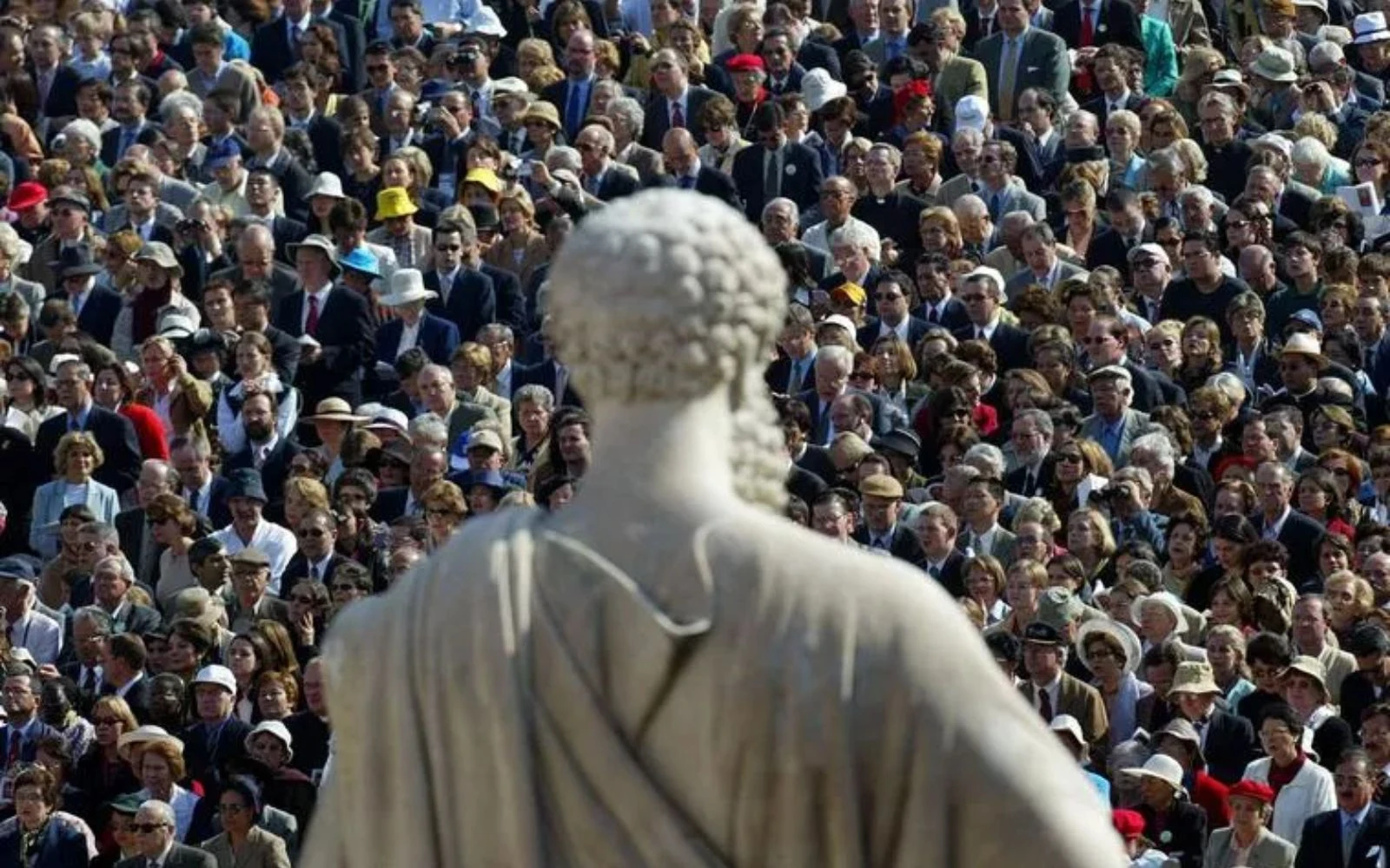 Los peregrinos se encuentran frente a una estatua de San Pedro, en la Plaza de San Pedro del Vaticano, mientras el Papa Juan Pablo II oficia la misa de canonización del fundador del Opus Dei, San Josemaría Escrivá de Balaguer, el 6 de octubre de 2002. Se estima que 250.000 peregrinos de todo el mundo asistieron a la ceremonia.?w=200&h=150