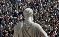 Los peregrinos se encuentran frente a una estatua de San Pedro, en la Plaza de San Pedro del Vaticano, mientras el Papa Juan Pablo II oficia la misa de canonización del fundador del Opus Dei, San Josemaría Escrivá de Balaguer, el 6 de octubre de 2002. Se estima que 250.000 peregrinos de todo el mundo asistieron a la ceremonia.