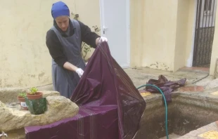 Una religiosa del Instituto del Verbo Encarnado lava una casulla estropeada por el barro en España. Crédito: Instituto del Verbo Encarnado