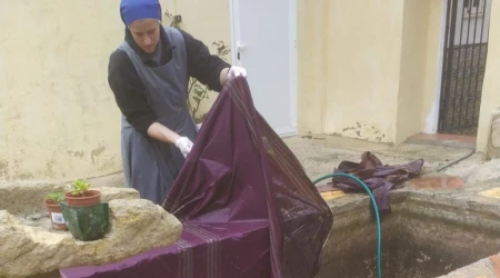 Una religiosa del Instituto del Verbo Encarnado lava una casulla estropeada por el barro en España.