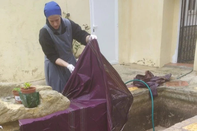 Una religiosa del Instituto del Verbo Encarnado lava una casulla estropeada por el barro en España.