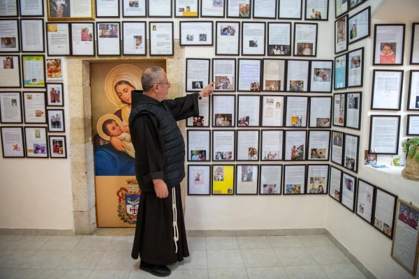 El P. Luis Enrique Segovia señala unas cartas colgadas en la pared del despacho de los frailes, junto a la Gruta de la Leche en Belén, que dan testimonio del nacimiento de un niño atribuido a la intercesión de la Virgen. Crédito: Marinella Bandini