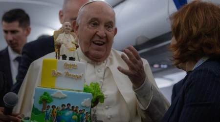 El Papa Francisco recibe una tarta de cumpleaños durante el vuelo de regreso de Córcega el 15 de diciembre