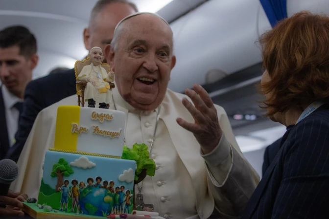 El Papa Francisco recibe una tarta de cumpleaños durante el vuelo de regreso de Córcega el 15 de diciembre