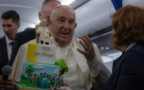 El Papa Francisco recibe una tarta de cumpleaños durante el vuelo de regreso de Córcega el 15 de diciembre