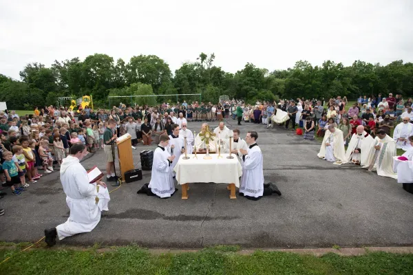 Los sacerdotes preparan la Eucaristía para la adoración en el asfalto de la escuela. Crédito: Jeffrey Bruno