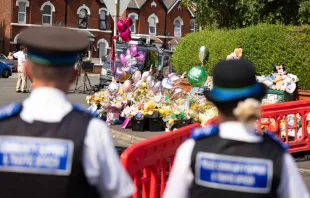 Policías de Inglaterra observan las ofrendas póstumas en memoria de las tres niñas asesinadas el lunes en  la ciudad de Southport. Crédito: Policía de Merseyside