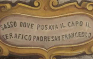 Placa sobre la reliquia donde se lee: "Piedra en la que apoyó su cabeza el serafín padre San Francisco". Crédito: Iglesia San Francesco a Ripa 