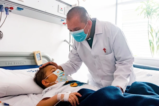 El sacerdote camiliano John Jairo Loaiza visita a un niño en un hospital de Bogotá.