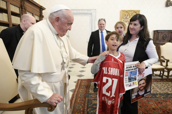 Niño entrega al Papa Francisco la camiseta con el nombre Tal Shoham. Crédito: Vatican Media