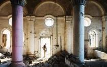 Un guardia de seguridad desconocido se encuentra en la entrada de una iglesia destruida durante los combates con ISIS en Mosul (Irak).