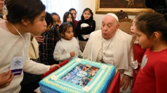 El Papa Francisco apaga las velas del pastel que le regalaron los niños.