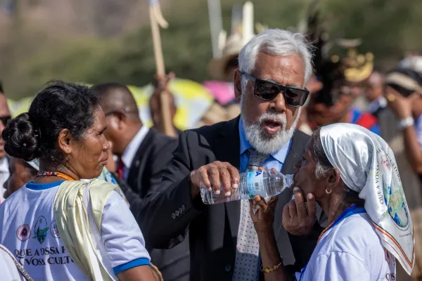 El Primer Ministro da agua a una mujer antes de que de inicio la Misa. Crédito: Daniel Ibáñez/EWTN News