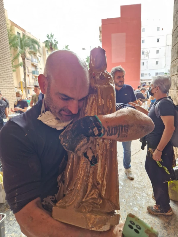 A volunteer saves an image of the Virgin Mary muddy. Credit: courtesy